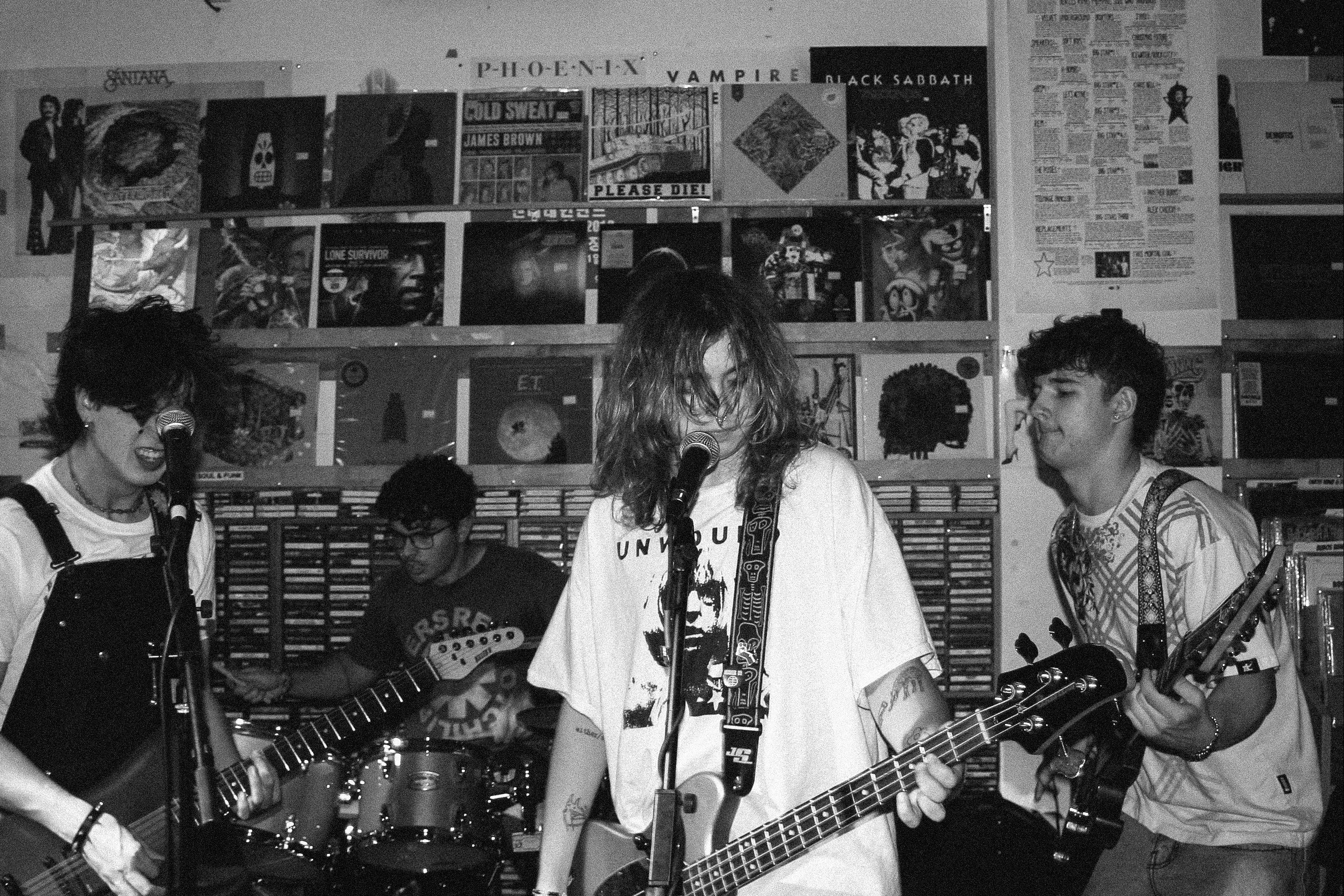 Band playing music in a record store with vinyl records on the wall.